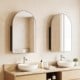 Brushed metal wall-mounted storage cabinet with arched mirror, featuring adjustable tempered glass shelves for elegant bathroom decor.