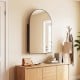 Arched mirror with brushed metal frame and adjustable shelves, perfect for wall-mounted storage in modern spaces.