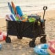 Heavy-duty collapsible wagon cart in black, loaded with beach gear, showcasing 4 all-terrain wheels for easy transport.