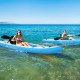 Two people kayaking in the ocean on a blue 10.8 feet inflatable kayak, perfect for water activities and easy transport.