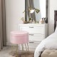 Round pink velvet storage ottoman with gold metal legs, perfect for a vanity or as a footrest in modern decor.