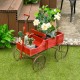 Red wooden wagon plant bed with wheels, featuring two planting sections, ideal for garden or patio decoration.