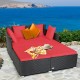 Spacious outdoor rattan daybed with red upholstered cushions, perfect for relaxation by the sea.