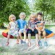 Oval 60-inch multicolor saucer swing with four children enjoying playtime outdoors, promoting friendship and.