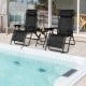 Two black folding zero gravity reclining lounge chairs with a table, perfect for outdoor relaxation by the pool.