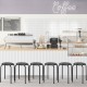Black stackable round metal stools with daisy pattern, ideal for indoor and outdoor use, shown in a café setting.
