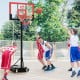 Kids playing basketball with a portable adjustable hoop system, featuring a shatterproof backboard and sturdy base.