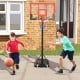 Kids dribbling a basketball near the portable adjustable hoop system, showcasing its black and red design for outdoor.