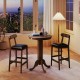 Round wood bar table set with pedestal base and two armless stools, ideal for intimate meals in a cozy setting.