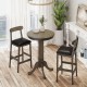 Round wood bar table set with pedestal base and two armless stools, perfect for intimate meals in a farmhouse style.