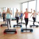 Group of women using the 3-in-1 aerobic step platform set for fitness training in a bright gym environment.