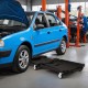 Foldable mechanic creeper with padded headrest and tool trays, designed for easy mobility and storage under cars.