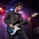Electric bass guitar in blue, showcasing a player in action with a gig bag, perfect for live performances and practice.