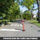Orange traffic delineator post with reflective collars on a street, ideal for guiding traffic and enhancing safety.