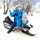 Two kids joyfully riding the Snow Racer sled with textured grip handles and mesh seat on a snowy hill.