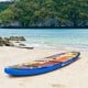 Inflatable stand-up paddle board in vibrant colors on the beach, ideal for water activities like surfing and yoga.