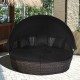 Round outdoor daybed with retractable canopy and black cushions, perfect for patio or poolside relaxation.