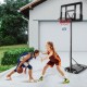 Two girls playing basketball near a 4.25-10 feet adjustable hoop system with shatterproof backboard.
