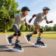 Two kids skating on adjustable light-up inline skates in a park, showcasing motion-activated LED wheels and protective.