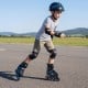Youth in blue adjustable roller skates with light-up wheels, showcasing safety gear while skating outdoors.