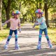 Two kids wearing adjustable purple roller skates with light-up wheels, enjoying a sunny day outdoors.
