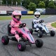 Kids riding pink 4-wheel pedal go-kart with adjustable seat and safe handbrake, perfect for outdoor fun.