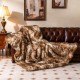 Luxurious 540GSM faux raccoon fur blanket draped over a brown leather sofa, ideal for cozying up on chilly nights.