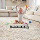 Baby playing with a 32-note glockenspiel xylophone on a plush rug, surrounded by colorful toys in a cozy living room.
