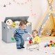 Kids playing with colorful blocks beside a gray wooden toy storage box with a cushion lid in a playroom setting.