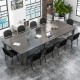 Long conference table with eight black office chairs featuring padded cushions and metal frames, ideal for meetings.