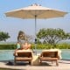9ft beige patio umbrella with aluminum pole, providing shade for outdoor lounging by the poolside.