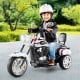 Toddler riding a black and white 3-wheel motorbike toy with headlight and horn, designed for stability and comfort.