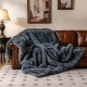 Gray plush faux wolf fur blanket draped over a leather sofa, featuring a soft texture and double-sided design for.