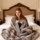 Soft plush fuzzy luxury faux fox fur blanket in brown, draped over a bed, perfect for cozying up with a warm drink.