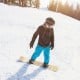Child snowboarding on a sturdy wooden snowboard with adjustable foot straps, perfect for learning and outdoor fun.
