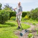 Man using an 18-inch rolling lawn aerator with anti-slip handle and tine spikes for efficient lawn care.