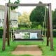 Spacious 2-person patio wicker hanging swing chair in black with acacia wood armrests, ideal for backyard relaxation.