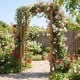 Wooden garden arch trellis in rustic brown, supporting climbing plants, ideal for outdoor weddings and decorative.