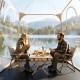 Clear bubble tent with two people enjoying a meal, showcasing the waterproof pod's spacious interior for outdoor.