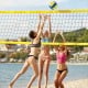 Portable outdoor volleyball net set in use on the beach, featuring a heavy-duty yellow net and adjustable poles.