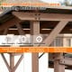Cedar wood frame grill gazebo with a powder-coated metal roof and two side serving shelves for outdoor gatherings.