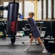 Child practicing boxing with a 40lbs filled punching bag and gloves, ideal for training in martial arts and fitness.