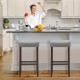 Set of 2 gray nailhead saddle bar stools with 29-inch height, featuring solid rubberwood legs and cushioned seats for.