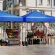 Pop-up canopy tent in blue, 9.5 x 9.5 feet, providing shade for outdoor markets and events with adjustable heights.