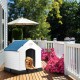 Durable plastic waterproof dog house with ventilated roof, providing a cozy outdoor shelter for pets on a sunny deck.