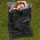 Couples sleeping in a black waterproof sleeping bag with two pillows, perfect for camping and outdoor activities.