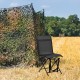 Black foldable 360-degree swivel chair with iron frame, set in a field, ideal for outdoor use and stability.
