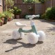 Green baby balance bike showcasing a side view with stable triangular structure and glowing wheels for enhanced safety.