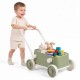 Toddler pushing a green Baby Push Walker with wheels, filled with toys and building blocks for imaginative play.