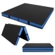 Thick black bi-fold gymnastics mat with blue edges, featuring carrying handles for easy transport and storage.